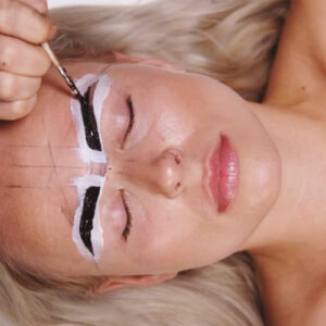 a woman receiving henna on her eyebrows